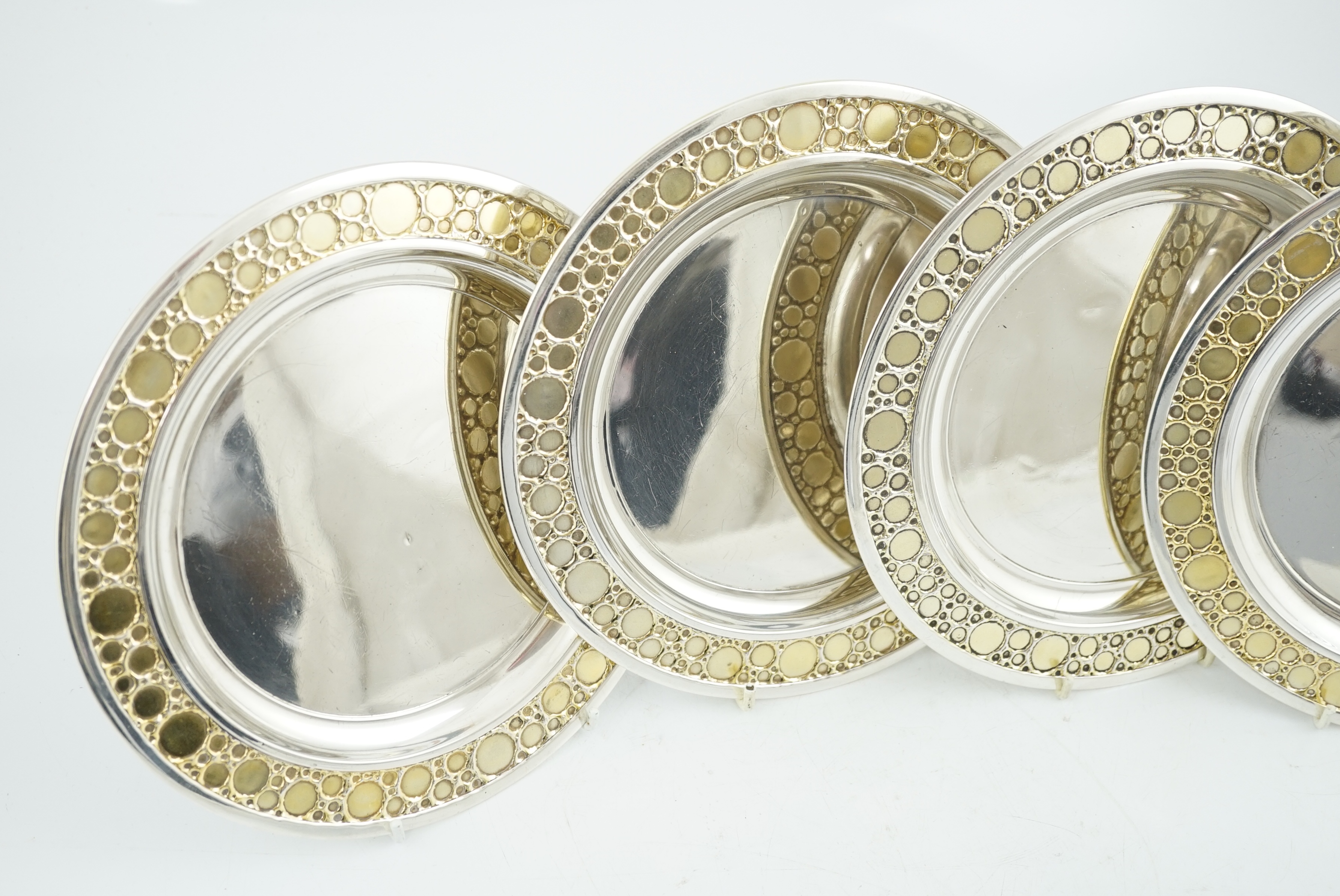 A set of four Elizabeth II Stuart Devlin parcel gilt silver circular plates